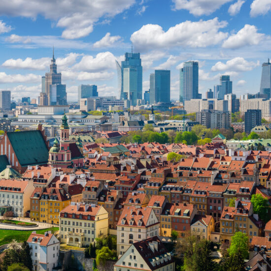 Warsaw old town and distant city center, PKiN and skyline under blue cloudy sky aerial landscape