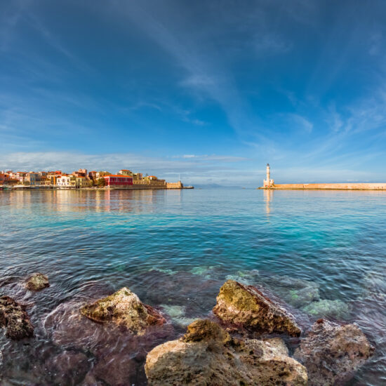 Panorama of the beautiful old harbor of Chania with the amazing lighthouse, mosque, venetian shipyards, at sunset, Crete, Greece