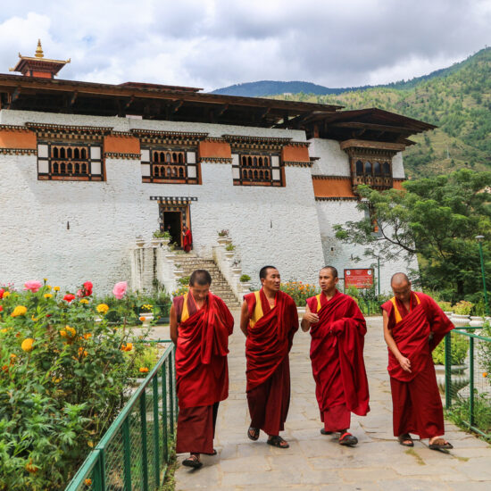 Four monks walking in the garden of Simtokha Dzong, Thimphu, Bhutan