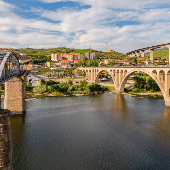 A steel bridge for pedestrians and two bridges for traffic cross the Douro River at Peso da Regua, Portugal