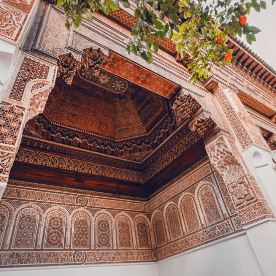 Intricate carvings and geometric patterns adorn the walls and ceiling of Bahia Palace, showcasing traditional Moroccan artistry
