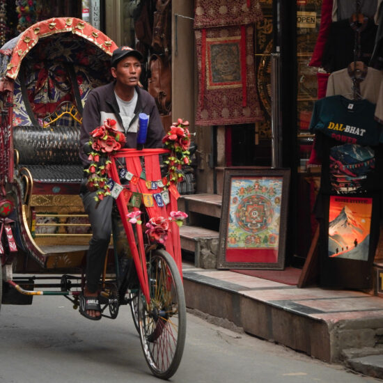 Nepalese traditional Cycle rickshaw on the streets of Kathmandu are bustling with traffic and lined with multi storey buildings in densely populated areas.