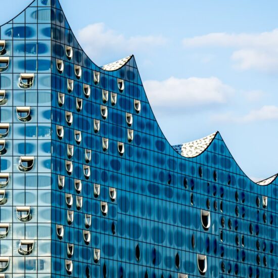 Close up of the striking silhouette of Hamburg Elbphilharmonie concert hall glass top, showcasing its glossy and futuristic wave design against blue sky, one of the most popular landmarks in Hamburg.