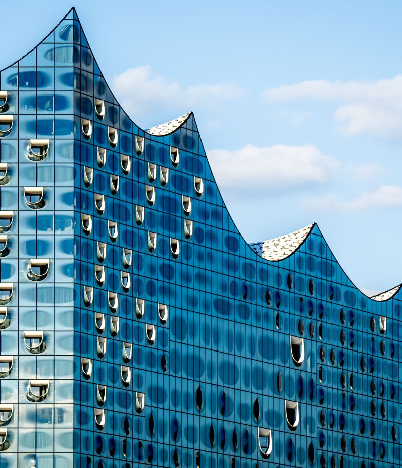 Close up of the striking silhouette of Hamburg Elbphilharmonie concert hall glass top, showcasing its glossy and futuristic wave design against blue sky, one of the most popular landmarks in Hamburg.