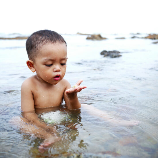 Portrait Of Happy Boy Playing In Water At Beach