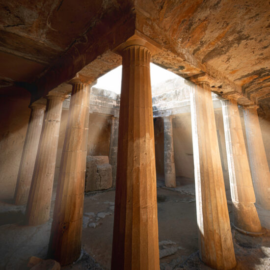 Sunbeams illuminate majestic columns inside an underground tomb in Tombs of the Kings archaeological site, Paphos, Cyprus