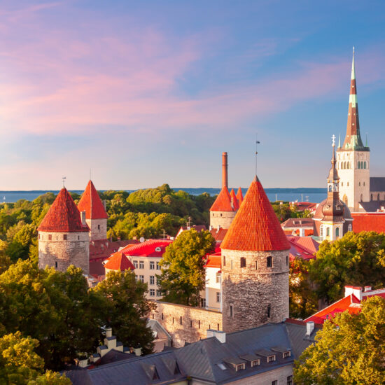 Classic Tallinn cityscape with St. Olav's church and old town walls and towers at sunset, Estonia
